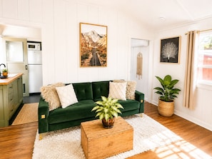 A living room with a green sofa, a wooden coffee table, and a large plant.