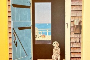 A dog sitting by a door with a view of a beach and sailboats. - Port Isabel Home close to SPI Beaches Big Yard, pets Family (Port Isabel)
