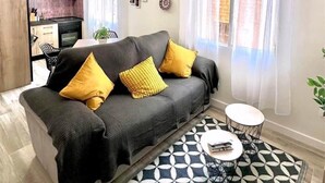 A modern living room with a sofa, a patterned rug, a small round table, and a ceiling fan. - ALMAVERA. Pure Calm House. Colibri 1 Apartment (Madrigal de la Vera)