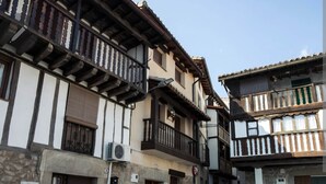 A narrow street with traditional half-timbered buildings, stone walls, and a clear sky. - ALMAVERA. Pure Calm House. Colibri 1 Apartment (Madrigal de la Vera)