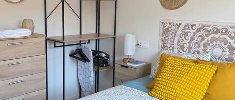 A neatly arranged bedroom with a bed, bedside table, and a wardrobe.