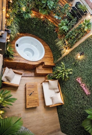 A hot tub surrounded by wooden furniture and lush greenery, with a neon sign reading 'Blue Chumba.' - Casa Murciélago🦇Located just off Calle 70-near restaurants and bars. (Medellín)