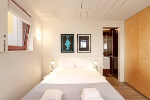 A hotel room with a large bed, two framed pictures on the wall, bedside lamps, and a wooden wardrobe. - VIVA - Lage Serviced Apartments 29A (Porto)