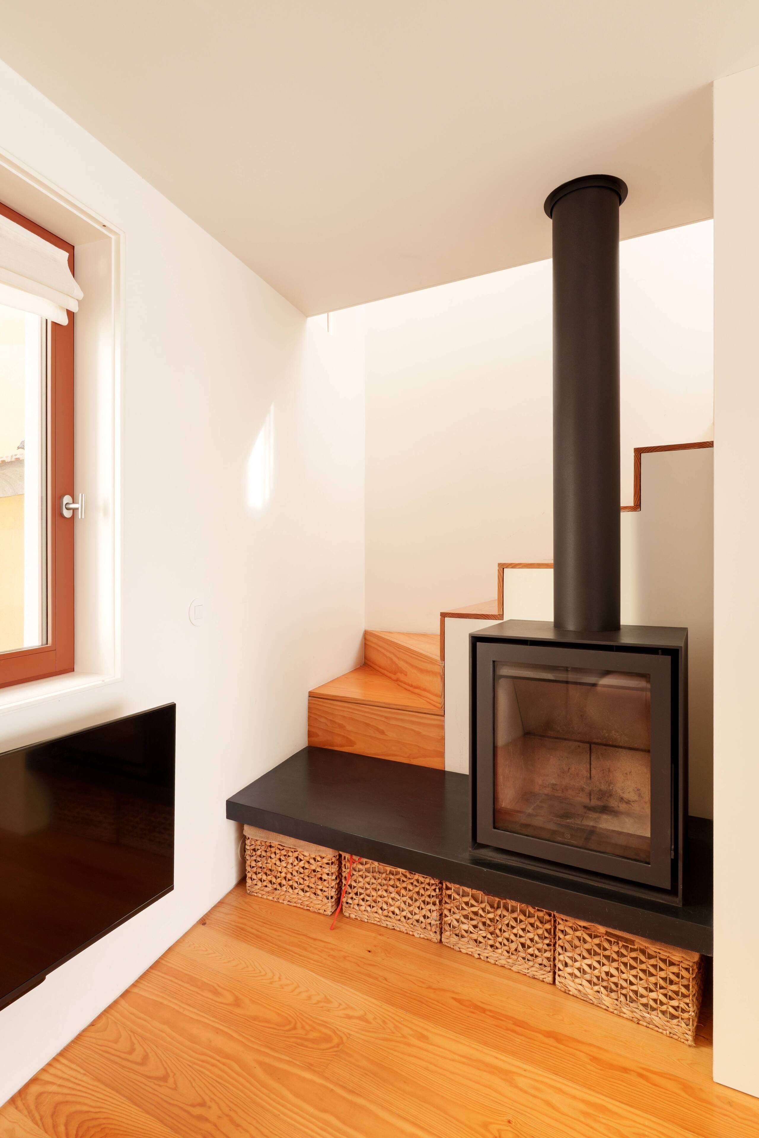 A modern interior with a built-in wood-burning stove, wooden flooring, and a staircase.