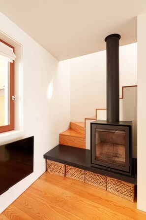 A modern interior with a built-in wood-burning stove, wooden flooring, and a staircase. - VIVA - Lage Serviced Apartments 29 (Porto)