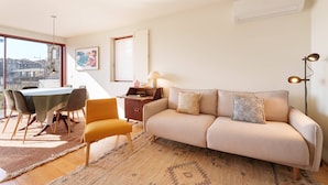A modern living room with a sofa, dining table, chairs, and a lamp. - VIVA - Lage Serviced Apartments 29 (Porto)
