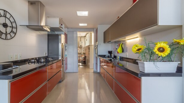 A modern kitchen with red cabinets, a stainless steel stove, and a clock on the wall. - Stunning View of Sugarloaf Mountain - Pb1201 (Rio de Janeiro)