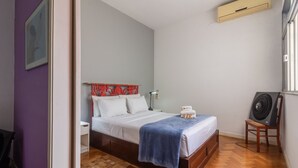 A bedroom with a bed, a bedside table, a lamp, a fan, and a window. - Stunning View of Sugarloaf Mountain - Pb1201 (Rio de Janeiro)