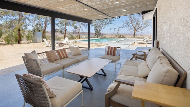 Une terrasse extérieure avec une piscine, un espace salon et une vue sur le paysage.