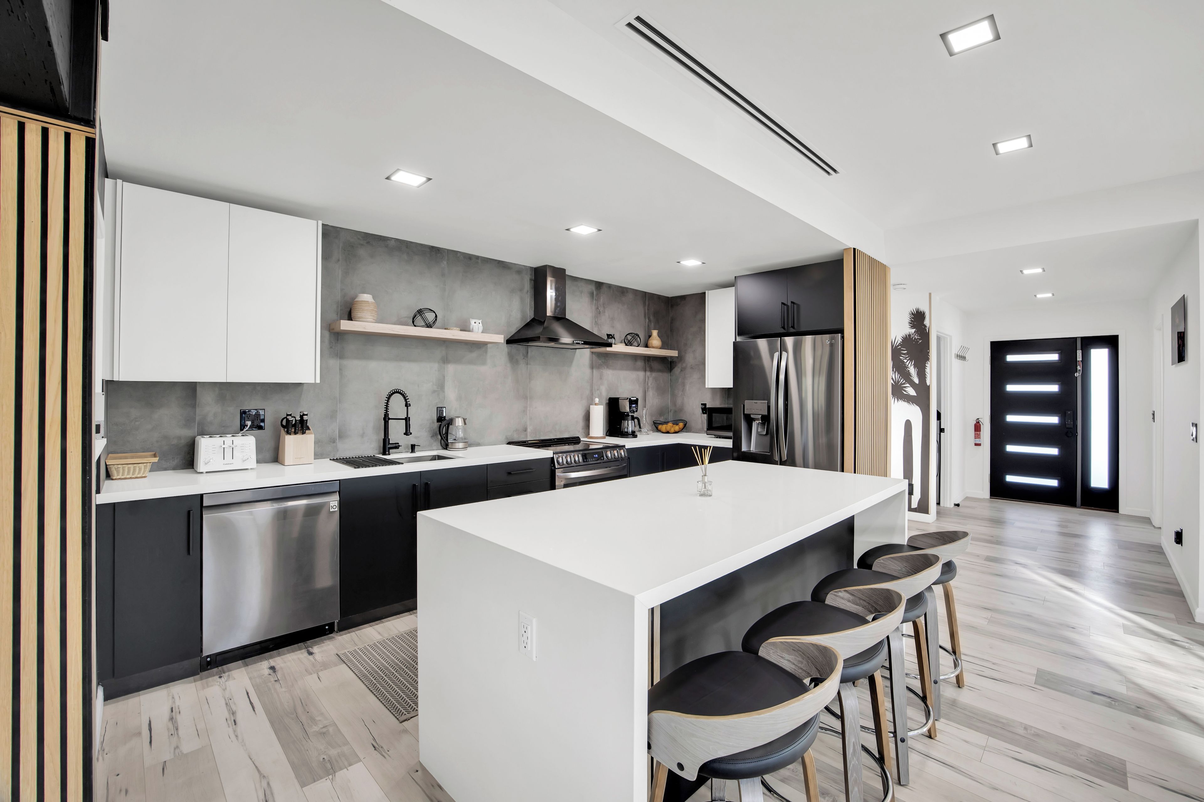 Una cocina moderna con una isla central, armarios negros y electrodomésticos de acero inoxidable.