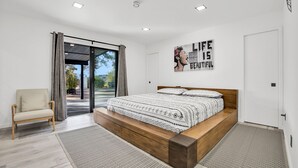 Une chambre moderne avec un grand lit, un canapé et une porte-fenêtre coulissante donnant sur un espace extérieur.