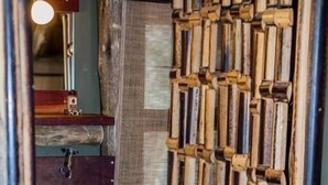 Une salle de bain rustique avec un mur en bois, un lavabo blanc et un rideau en bambou suspendu.