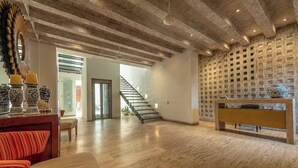 Ein großzügiger Wohnbereich mit Holzboden, einer Treppe und einer Wand mit strukturierter Oberfläche.
