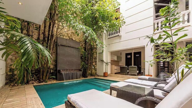 Ein Poolbereich mit Holzterrasse, Liegestühlen und einem Wasserfall.