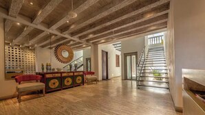 Ein geräumiger Raum mit Holzboden, einer Treppe und einem großen Spiegel.