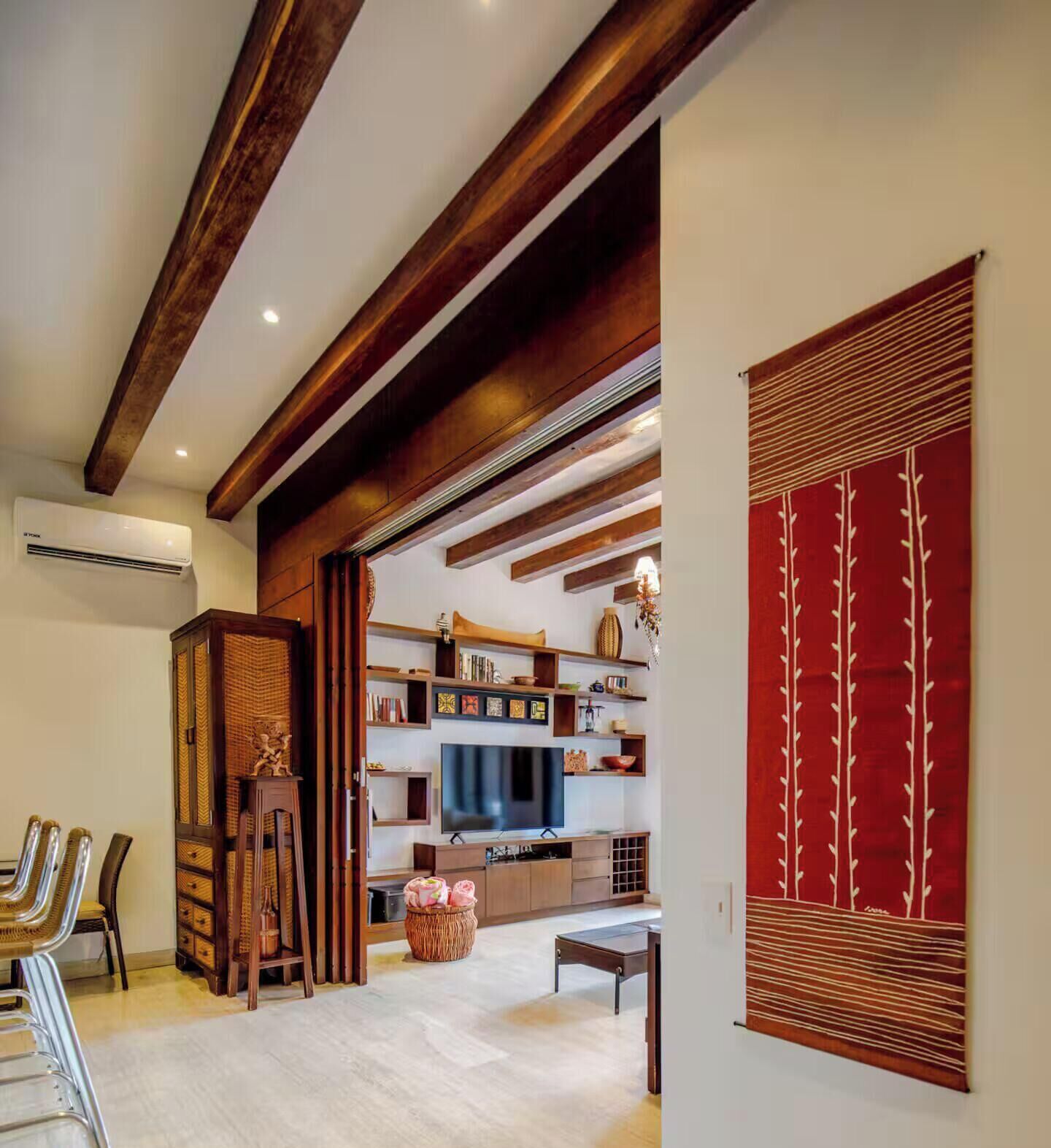 Un salon moderne avec des poutres apparentes, un téléviseur à écran plat et un panneau décoratif rouge.