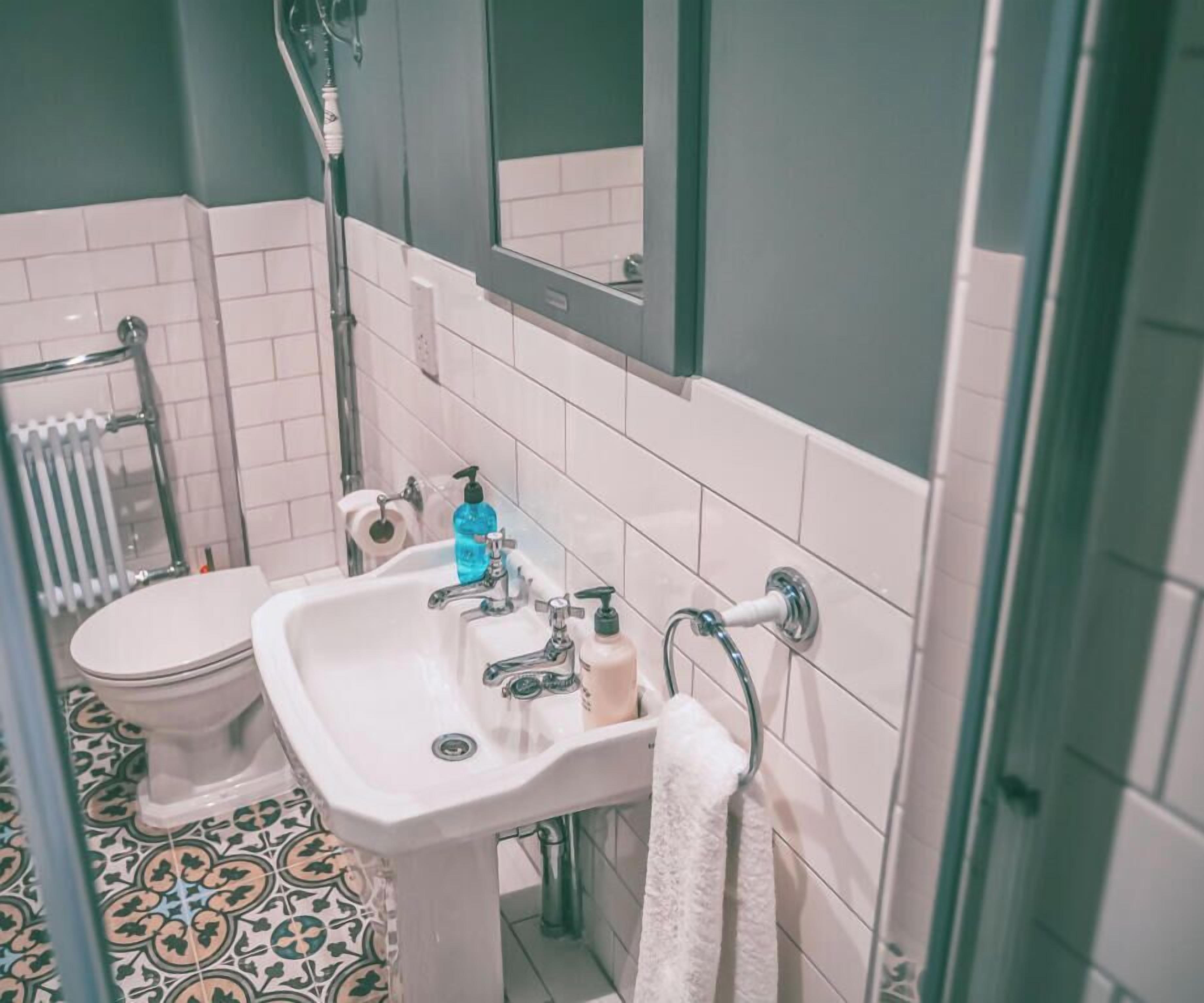 Une salle de bain avec un lavabo blanc, un miroir et des toilettes.