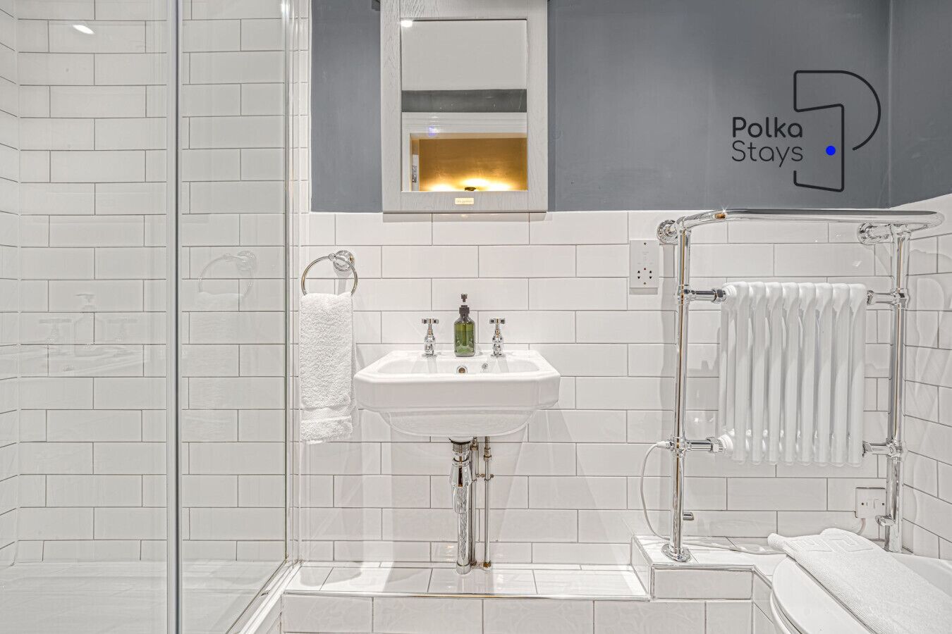 A modern bathroom with a glass shower enclosure, a white sink, and a towel rack.