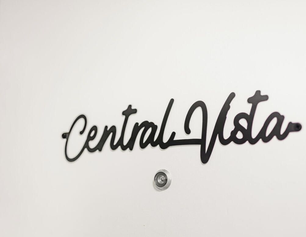 A sign with the text "Central Vista" on a white wall.