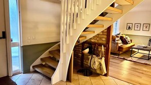 Een modern interieur met een houten trap, een stenen muur en een gezellige zithoek met kussens.