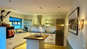 Een moderne keuken met witte kasten, een centraal eiland en een roestvrijstalen koelkast.
