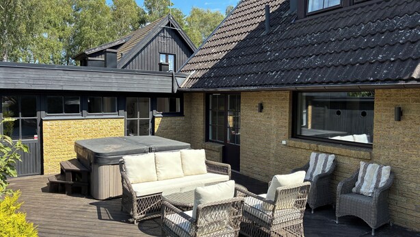 Een terras met rieten meubels, een jacuzzi en een stenen muur.