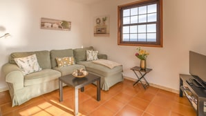 Uma sala de estar com sofá, mesa de centro, rack para TV e janela com vista.