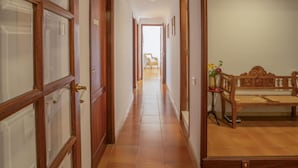 Um corredor com portas de madeira e um banco com um vaso de flores.