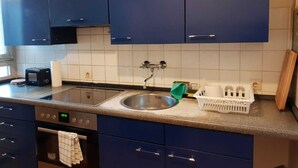 Una cocina con armarios azules, un lavamanos de acero inoxidable, un tostador y un reloj digital que muestra las 20:40.