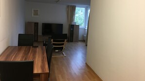 Una habitación con una mesa de comedor de madera, sillas, un televisor y una ventana con cortinas.