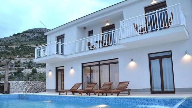 A modern two-story building with a swimming pool, lounge chairs, and a balcony with white railings. - Villa Katarina 5-bedroom near Dubrovnik with private pool (Ivanica)