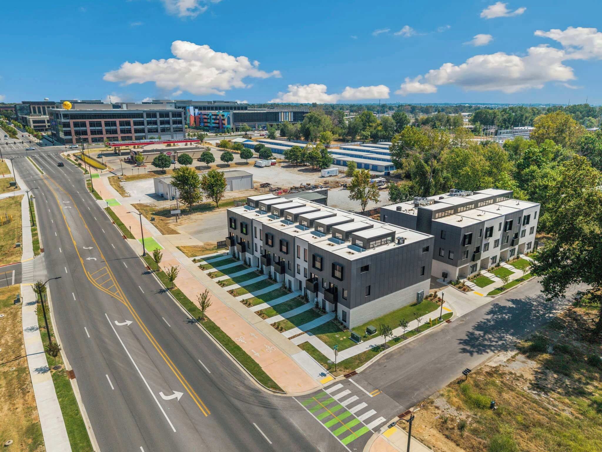 A modern building complex with multiple floors, a parking lot, and a road with marked lanes.