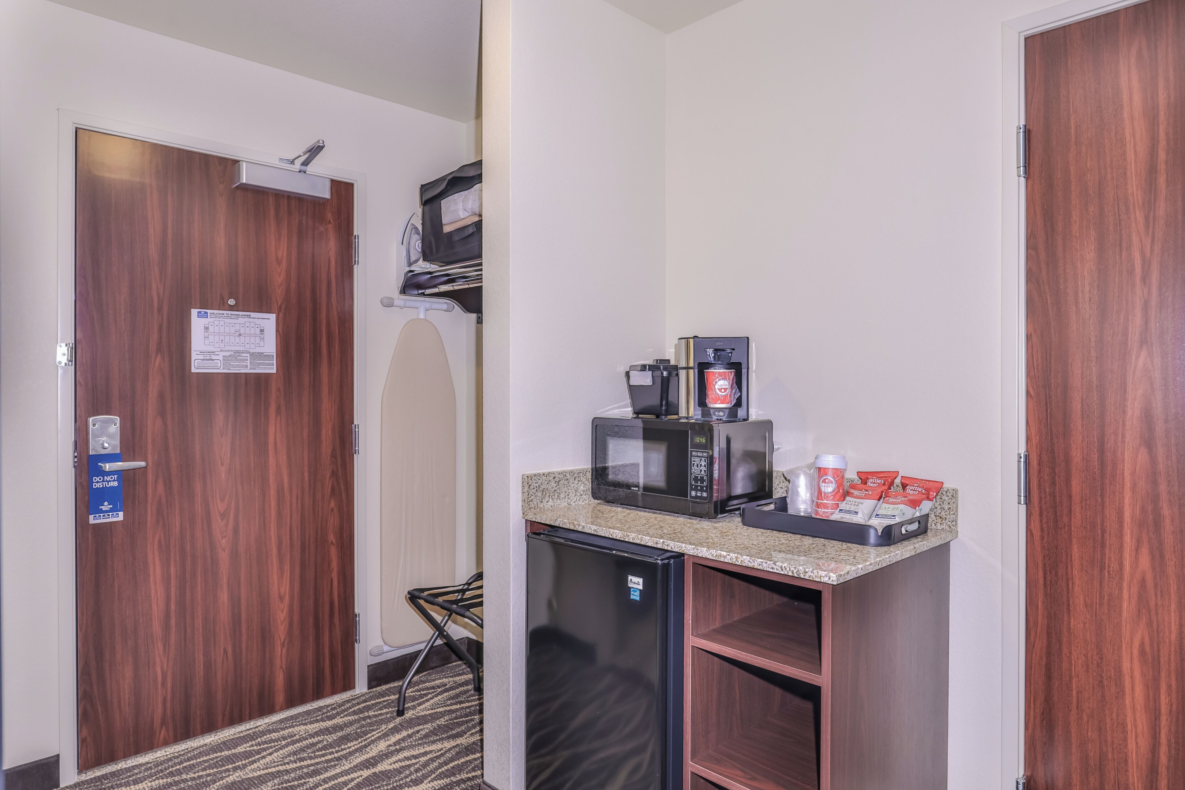 Une chambre d’hôtel compacte équipée d’une kitchenette, d’un four à micro-ondes, d’un réfrigérateur et d’un petit coin salon.