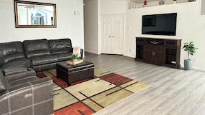 A modern living room with a leather sofa, a coffee table, a TV, and a ceiling fan. - Charming 3-bedroom house Peaceful wine country Home Near Sedona & Jerome (Clarkdale)