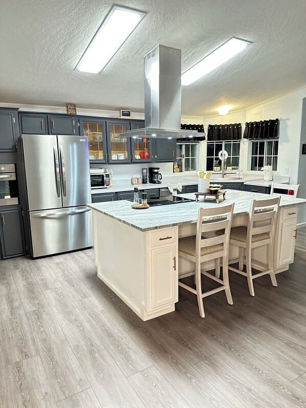A modern kitchen with a central island, stainless steel appliances, and dark cabinetry.