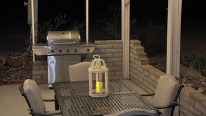 An outdoor patio with a grill, table, chairs, and string lights. - Charming 3-bedroom house Peaceful wine country Home Near Sedona & Jerome (Clarkdale)