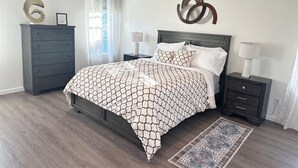 A bedroom with a bed, a dresser, a nightstand, a lamp, a rug, and decorative wall art. - Charming 3-bedroom house Peaceful wine country Home Near Sedona & Jerome (Clarkdale)