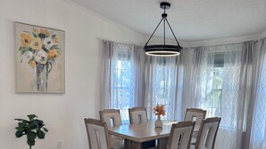 A dining area with a round table, six chairs, a potted plant, and a ceiling light fixture. - Charming 3-bedroom house Peaceful wine country Home Near Sedona & Jerome (Clarkdale)