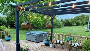 Une terrasse en bois agrémentée d’une pergola, de sièges d’extérieur et de jardinières suspendues.