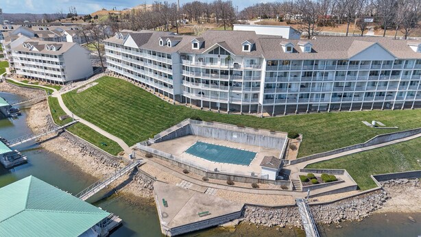 A large hotel with multiple balconies, a swimming pool, and a dock area.