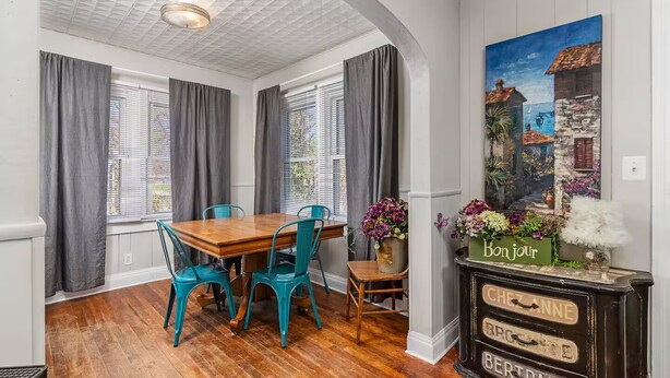 A dining area with a wooden table and teal chairs, a black cabinet with vintage-style labels, and a painting of a coastal scene. - Tuscan Inspired 3br Cottage (Lebanon)