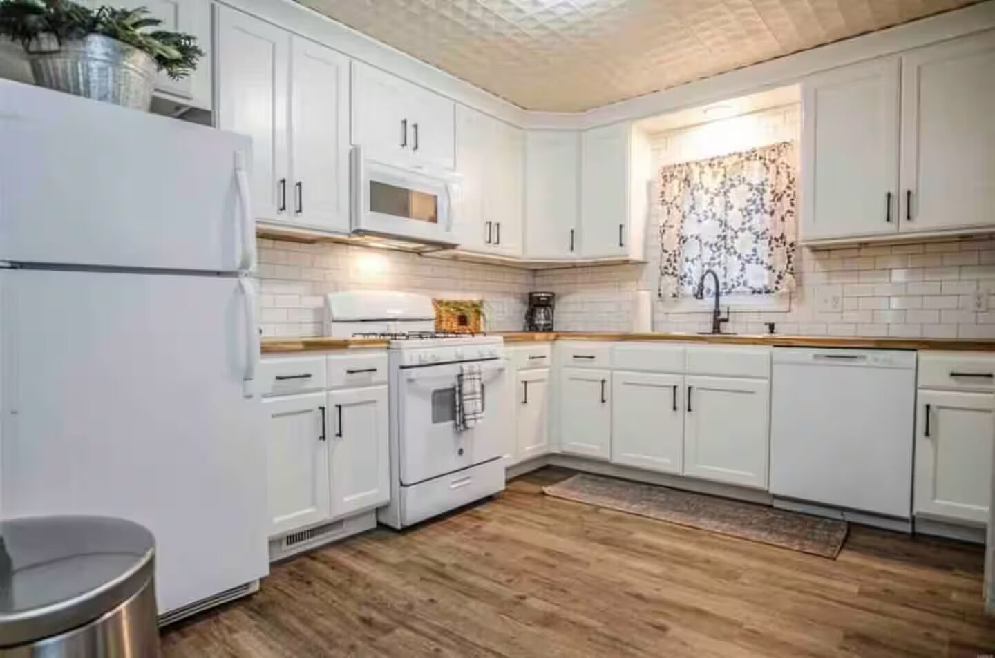 A kitchen with white cabinets, a stove, a microwave, and a dishwasher.