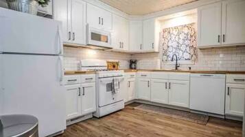 A kitchen with white cabinets, a stove, a microwave, and a dishwasher.