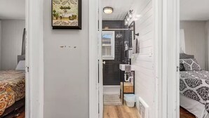 A narrow hallway leading to a bathroom with a bathtub, a sink, and a window. - Tuscan Inspired 3br Cottage (Lebanon)
