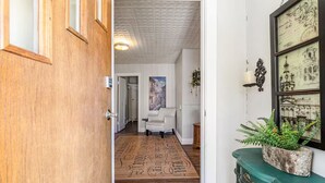 A hallway with a wooden door, a patterned rug, a white chair, and a green cabinet with a plant. - Tuscan Inspired 3br Cottage (Lebanon)