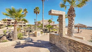 Ett semesterparadis med palmer, en stenmur och utsikt över stranden.