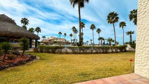 Ein Resort mit strohgedecktem Gebäude, Palmen und einem Poolbereich.