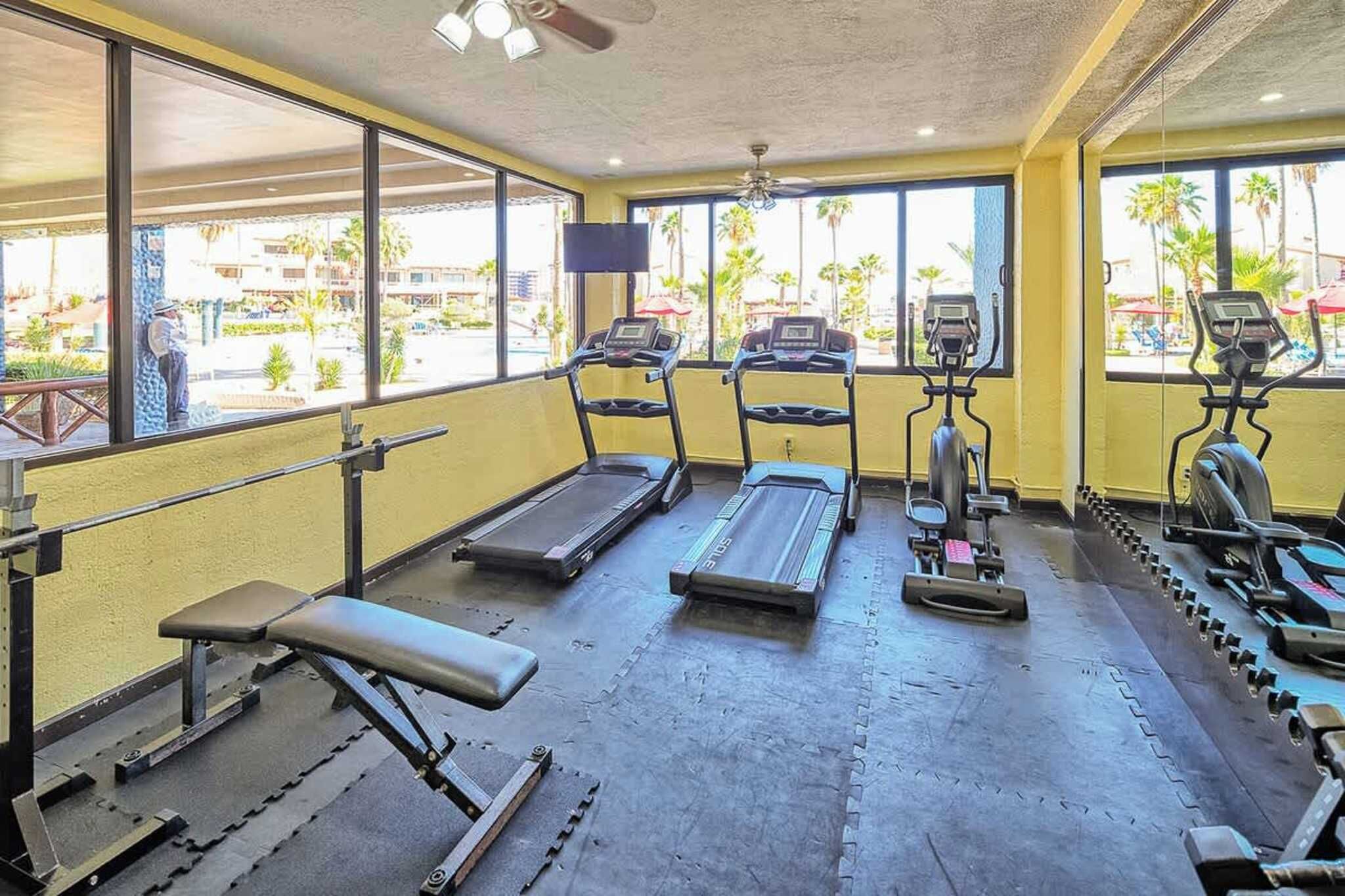 Une salle de sport équipée de tapis de course, d’un banc et d’appareils de musculation.