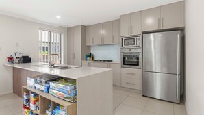 Een moderne keuken met een centraal eiland, roestvrijstalen apparatuur en diverse gezelschapsspellen.