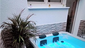 Een bubbelbad met jets, omringd door stenen muren en een potplant.